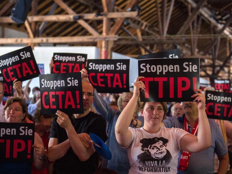 Kirchentagsteilnehmer halten bei einem Flashmob im Vorfeld einer Veranstaltung im Programm des deutschen evangelischen Kirchentags Schilder mit der Aufschrift "Stoppen Sie CETA!" und "Stoppen Sie TTIP"