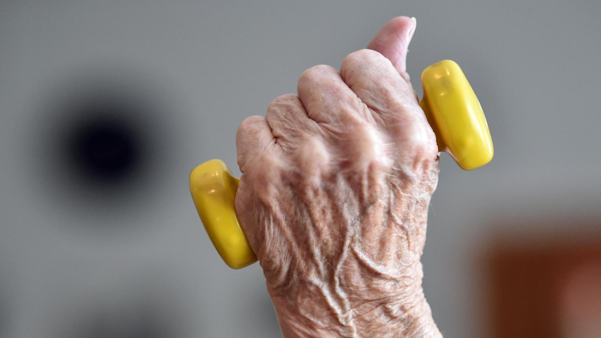 Eine Seniorin trainiert mit einer leichten Hantel. Man sieht nur die Hand mit der Hantel.