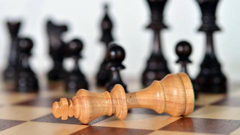 Die Schachfigur Weißer König liegt auf einem Schachbrett.