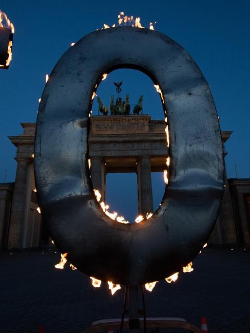 Bei einer Greenpeace-Aktion steht ein CO-2-Schriftzug, aus dem Flammen schlagen, vor dem Brandenburger Tor.