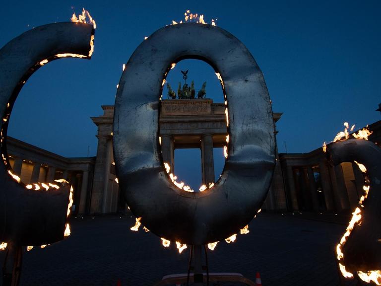 Bei einer Greenpeace-Aktion steht ein CO-2-Schriftzug, aus dem Flammen schlagen, vor dem Brandenburger Tor.
