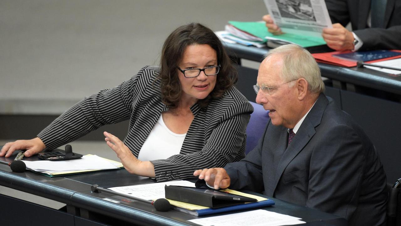 Bundesarbeitsministerin Nahles und Bundesfinanzminister Schäuble sitzen im Plenum nebeneinander und unterhalten sich.