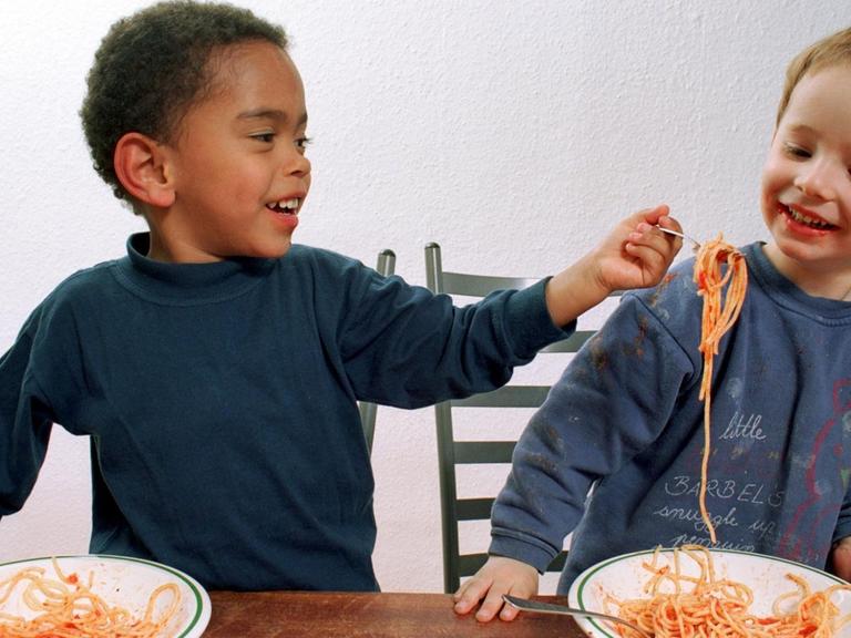 Zwei Jungen haben Spaß beim gemeinsamen Spaghetti-Essen.