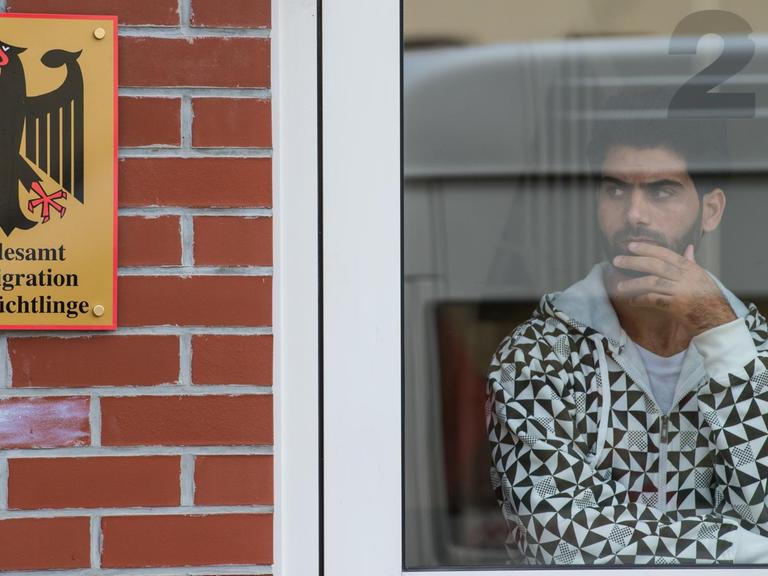 Ein Flüchtling schaut in Eisenhüttenstadt aus dem Fenster einer Erstaufnahmestelle.