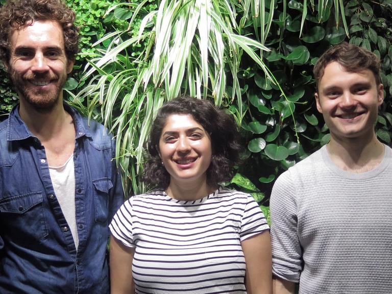 Die drei Poetryslammer Julian Heun,Tanasgol Sabbagh, Dominik Erhard stehen vor einer Pflanzenwand vor dem Studio 9 des Deutschlandfunk Kultur.