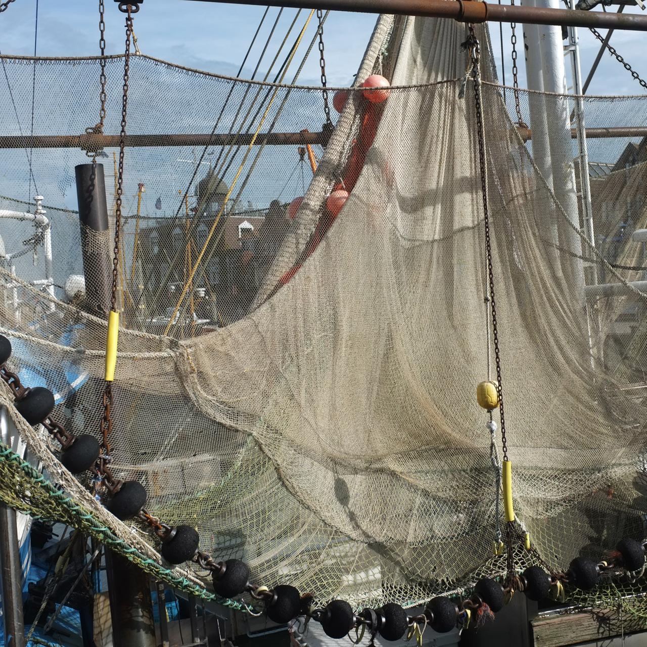 Ein Fangnetz ist auf einem Fischkutter aufgehängt.
