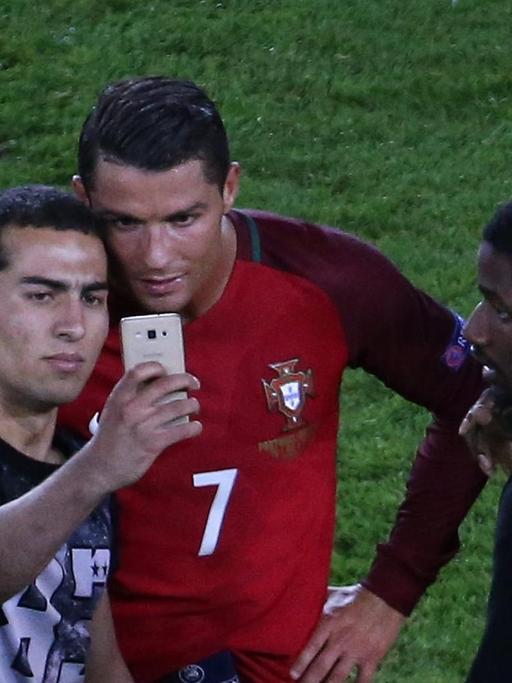 Ein aufs Feld gestürmter Fan macht nach dem EM-Spiel Portugal-Österreich ein Selfie mit Cristiano Ronaldo, bevor ihn die Ordner wegführen.