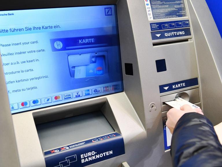 Jemand führt eine Bankkarte in einen Geldautomaten ein.