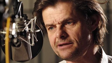 Der Schauspieler Lars Rudolph während einer Studioaufnahme am Mikrofon.