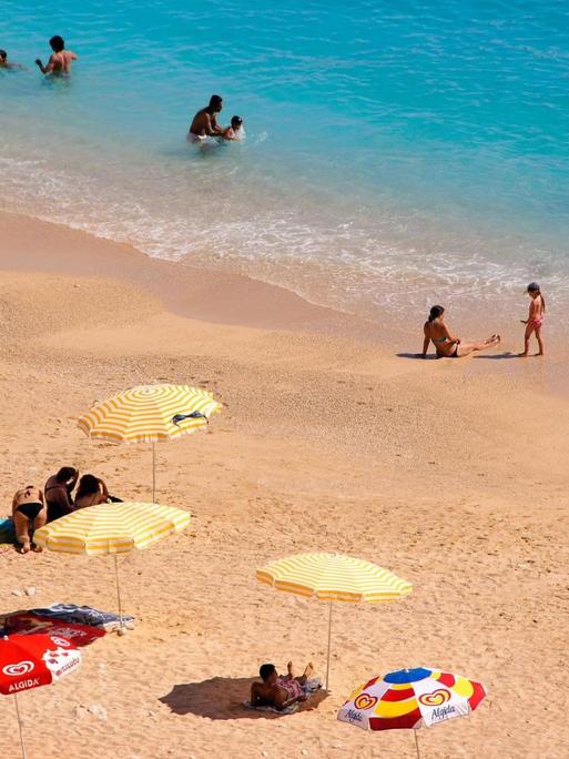 Sonnenschirme und Menschen am Strand in der Nähre von Kas in der Türkei