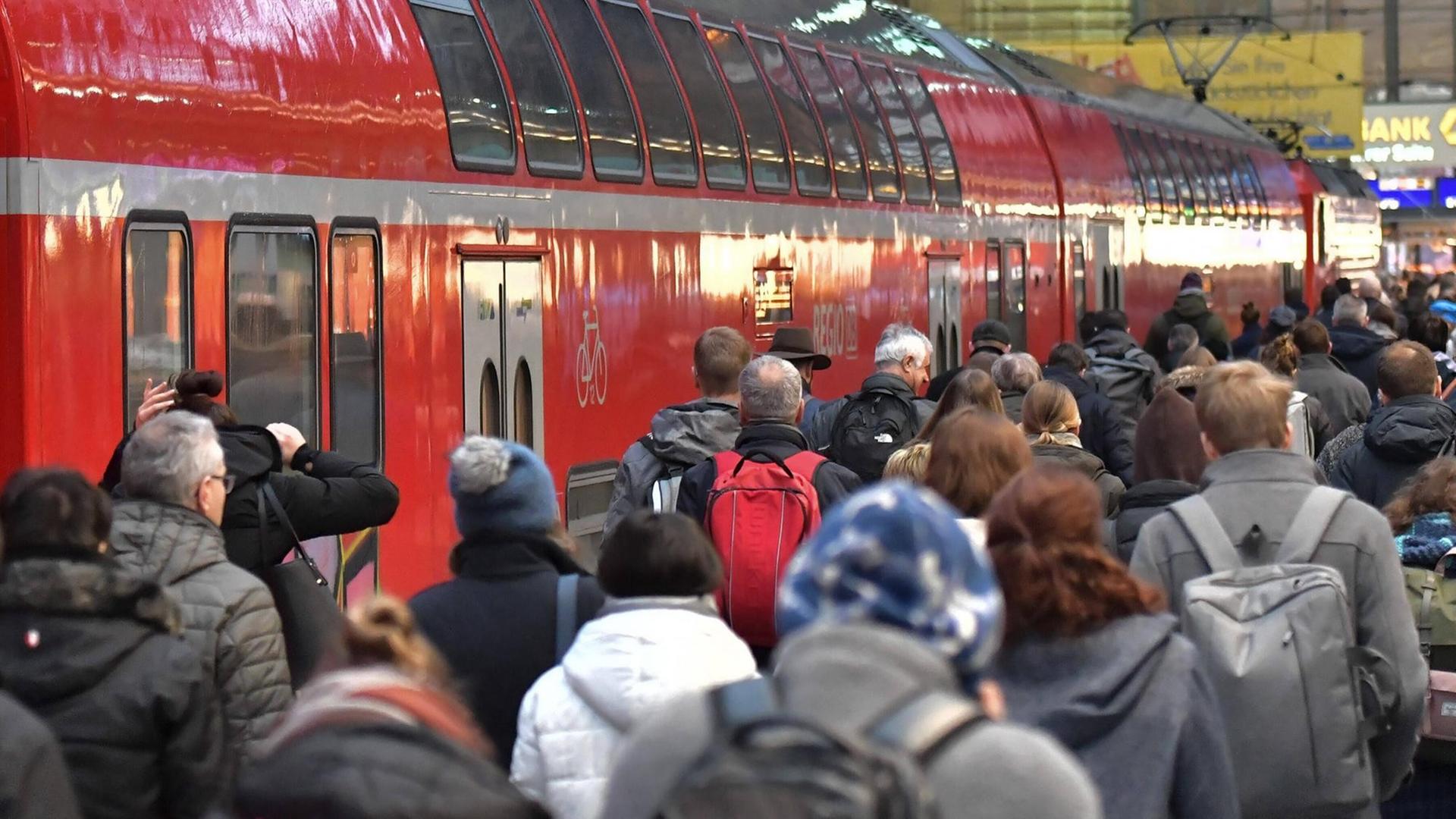 Zahlreiche Menschen gehen neben einem Zug der Deutschen Bahn.