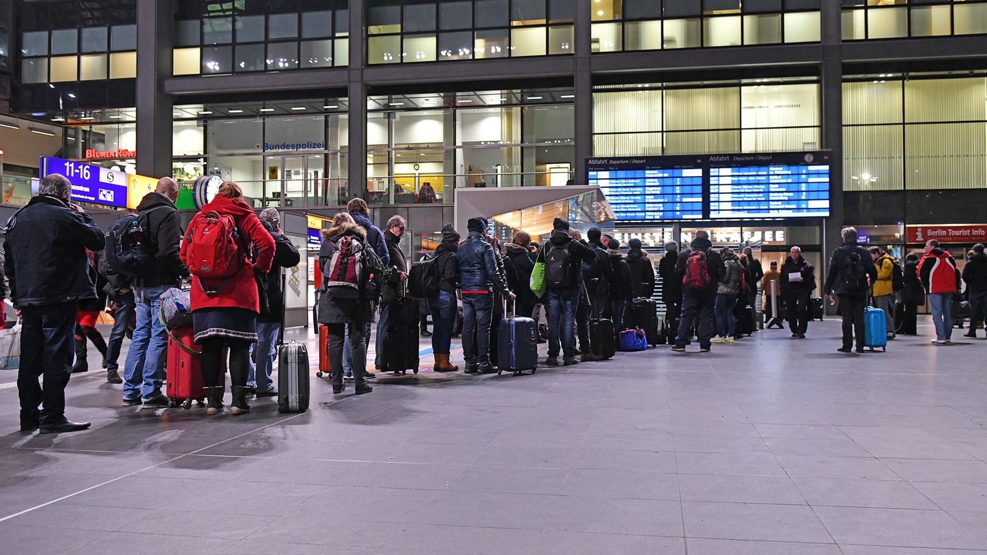 Reisende stehen Schlange an einem Informationsstand der Deutschen Bahn im Berliner Hauptbahnhof.