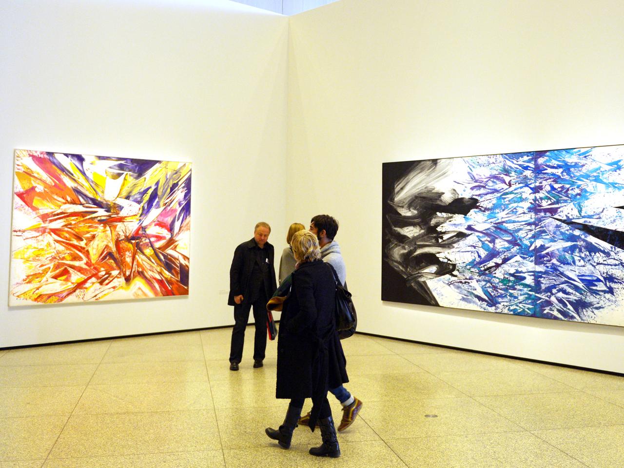 Besucher in der Werkschau von K.O. Götz in der Neuen Nationalgalerie vor abstrakten Malereien des Künstlers.