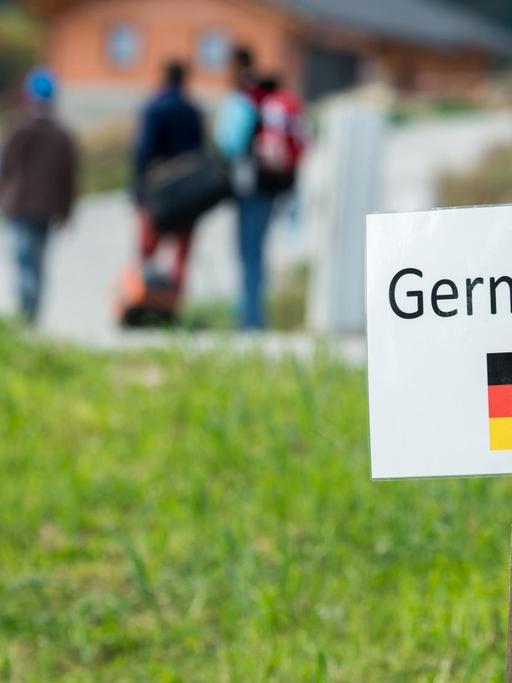 Flüchtlinge auf dem Weg von Österreich nach Bayern. Ein Schild weist den Weg nach Deutschland.