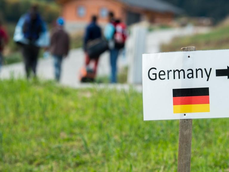 Flüchtlinge auf dem Weg von Österreich nach Bayern. Ein Schild weist den Weg nach Deutschland.