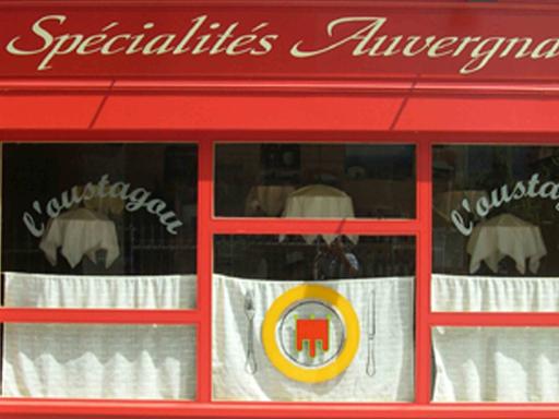 Französisches Restaurant in der Auvergne: Rote Fassade, weiße Vorhänge in den Fenstern.