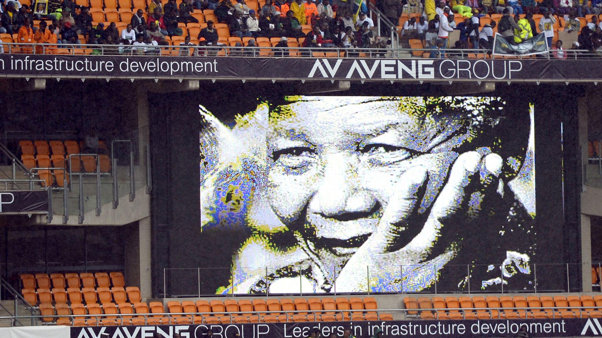 Im mit Menschen gefüllten Fußballstadion von Johannesburg hängt ein Mandela-Plakat