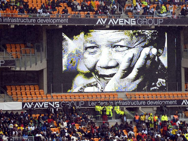 Im mit Menschen gefüllten Fußballstadion von Johannesburg hängt ein Mandela-Plakat