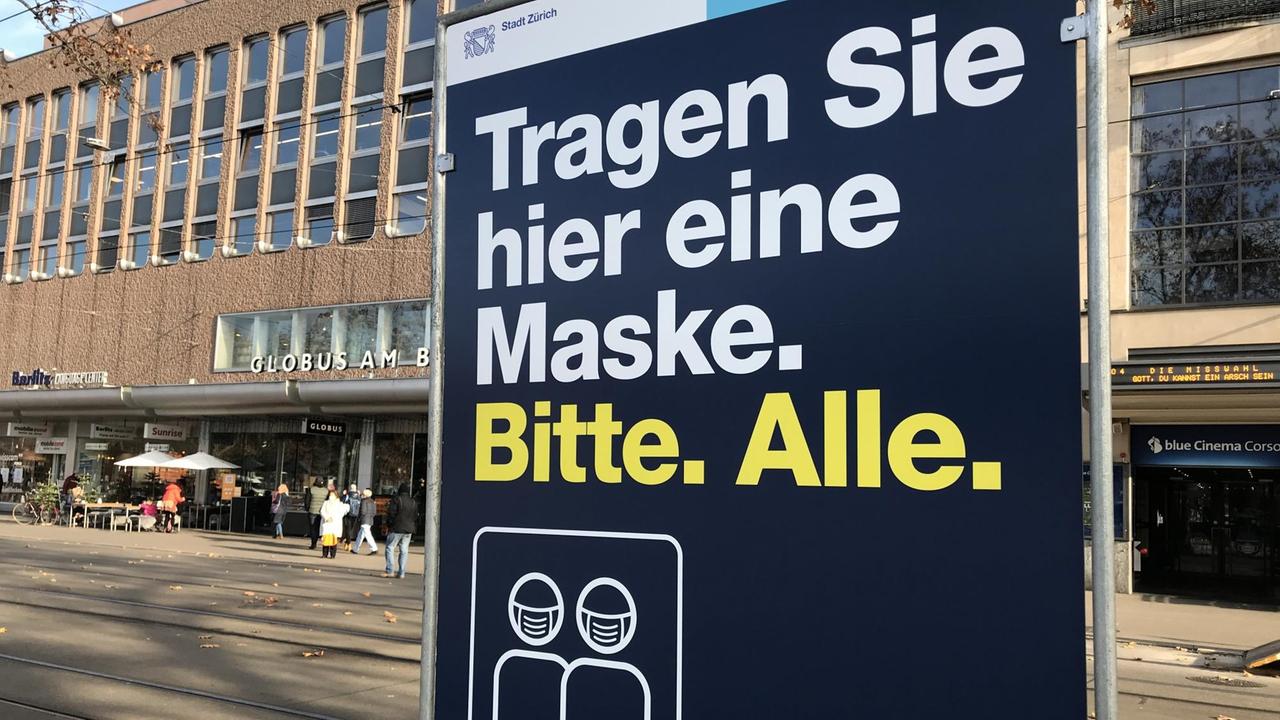 Ein Schild in der Zürcher Innenstadt gebiettet, Maske zu tragen.