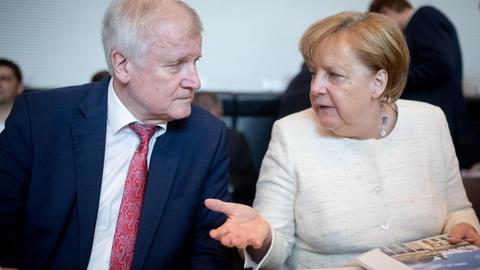 12.06.2018, Berlin: Bundeskanzlerin Angela Merkel (CDU) und Horst Seehofer (CSU), Bundesminister für Inneres, Heimat und Bau unterhalten sich Beginn der CDU/CSU-Fraktionssitzung im Bundestag.