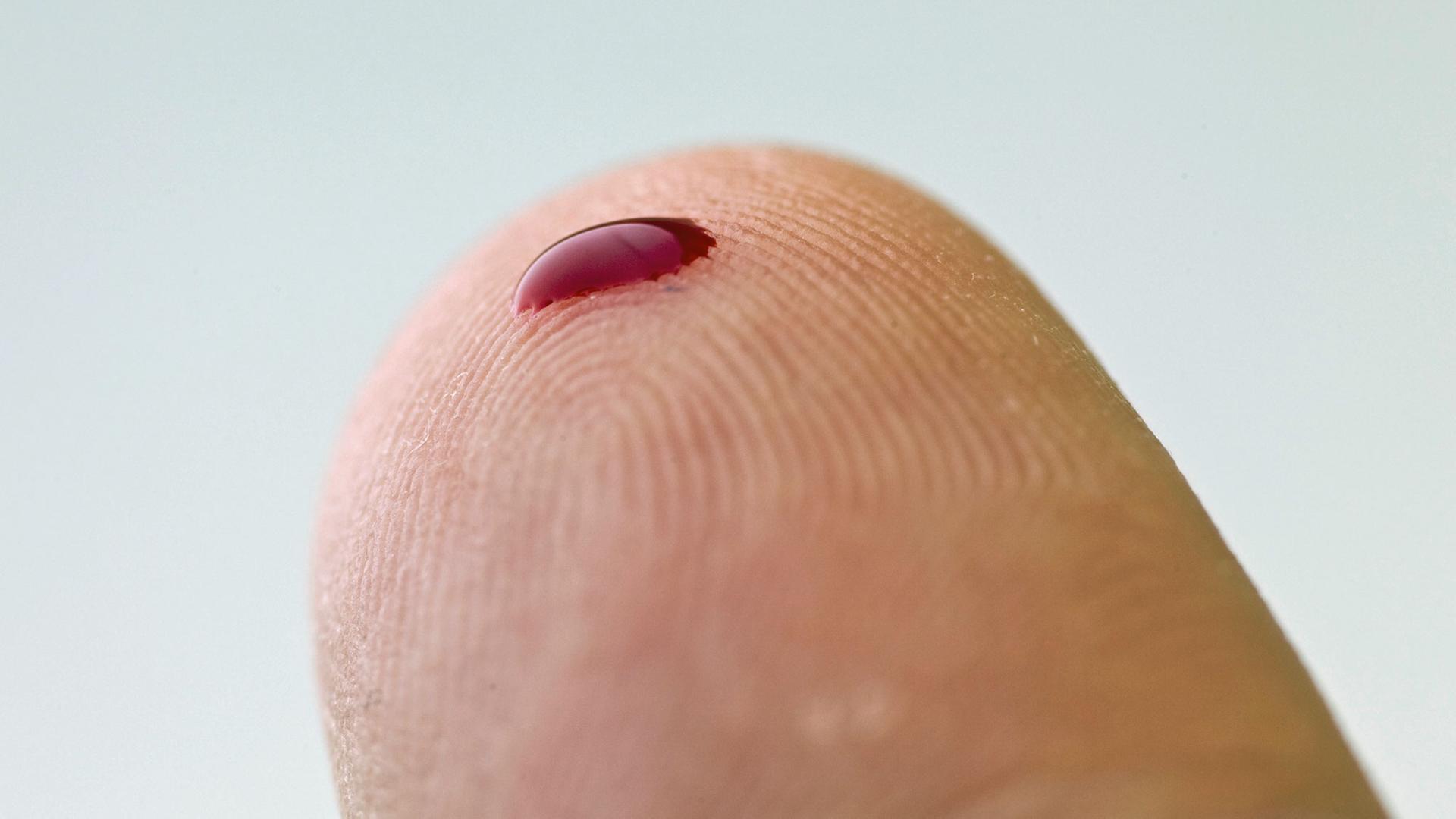 Ein kleiner Blutstropfen auf einem Finger. Mithilfe eines solchen Tropfens und eines Messgerätes können zum Beispiel an Diabetes erkrankte Menschen den Zuckergehalt des Blutes bestimmen.