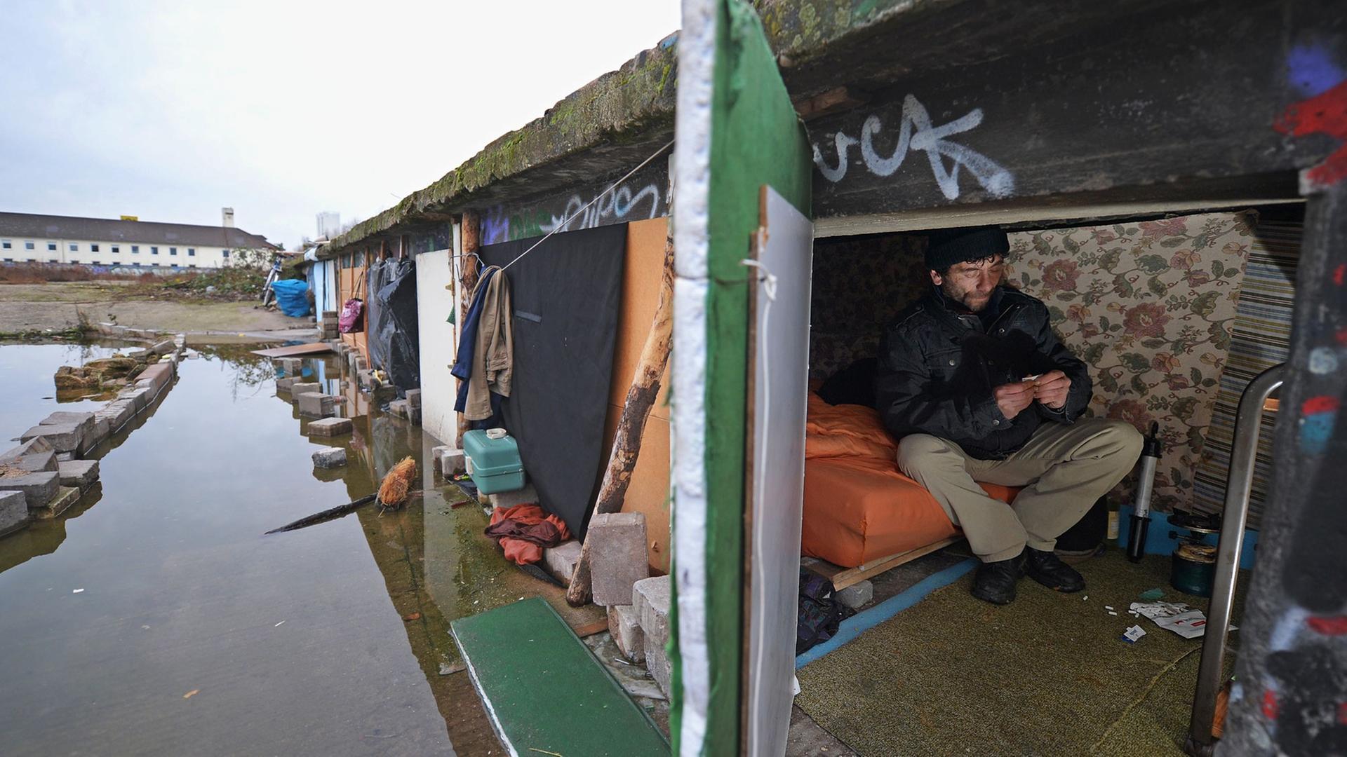 Eine Rumäne sitzt in Frankfurt am Main auf dem Gelände einer ehemaligen Möbelspedition in seiner notdürftig eingerichteten Unterkunft.
