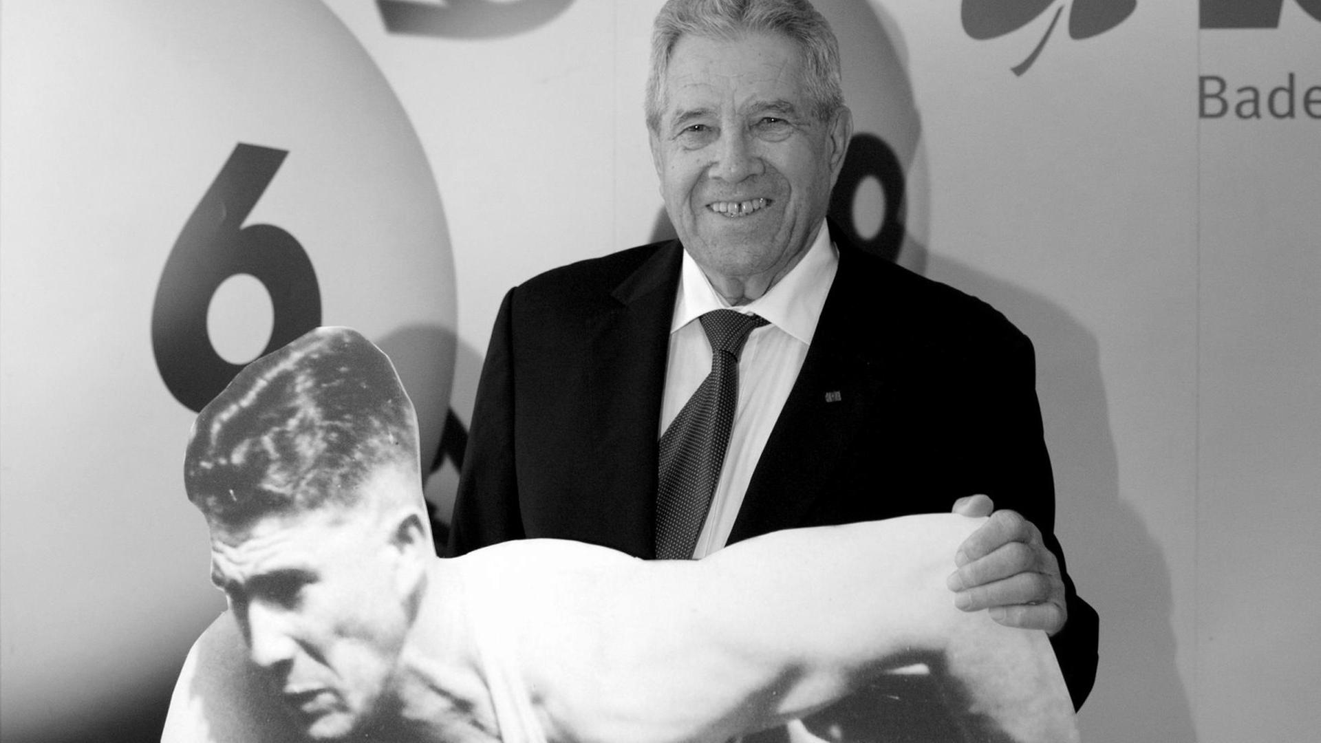 Der ehemalige Sprinter Heinz Fütterer lächelt am Mittwoch (12.10.2011) bei einem Empfang in Stuttgart hinter eine Pappfigur, die ihn am 28.08.1954 bei den Europa-Meisterschaften in Bern zeigt.