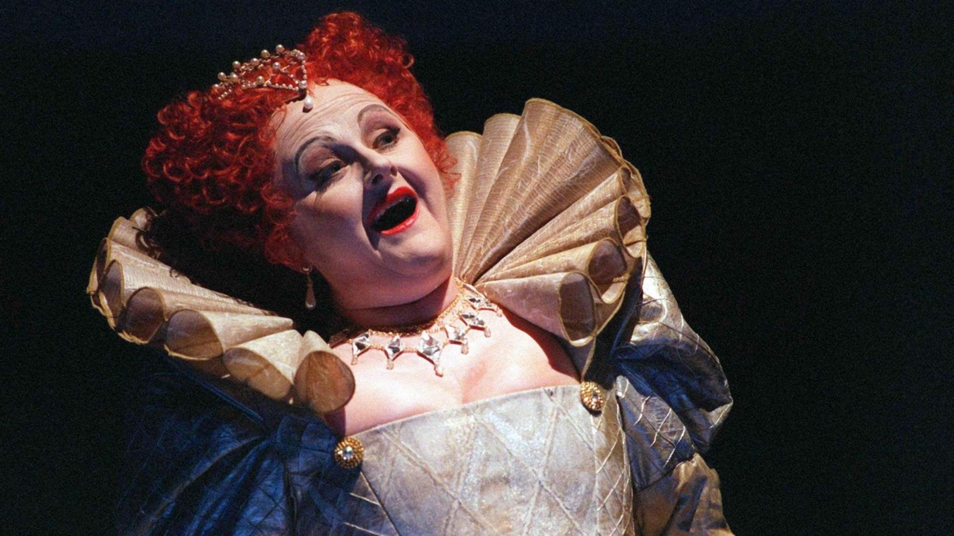 Eine Frau mit roter Perücke im viktorianischen Kostüm singt. Es handelt sich um Edita Gruberová.