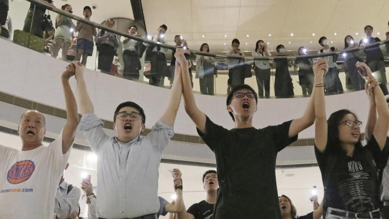 Demonstranten singen 2019 in einem Einkaufszentrum "Glory To Hongkong" und halten sich an den Händen.
