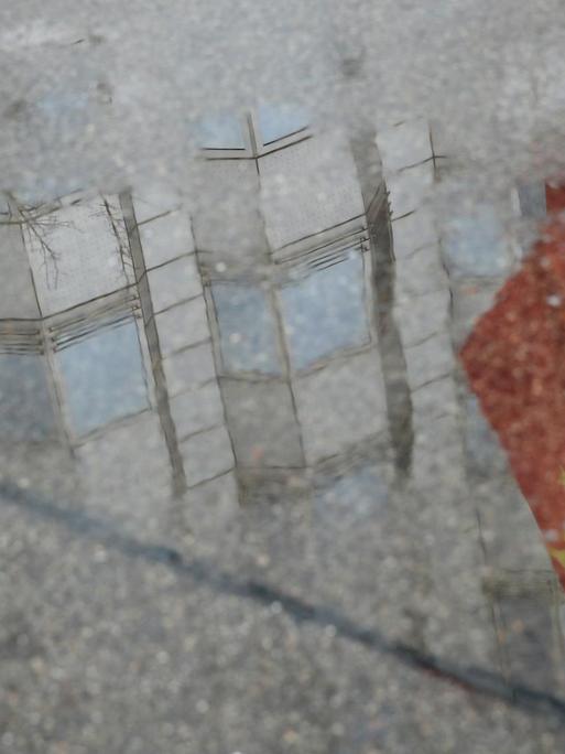 Die Flagge vor der chinesischen Botschaft in Berlin spiegelt sich in einer Pfütze.