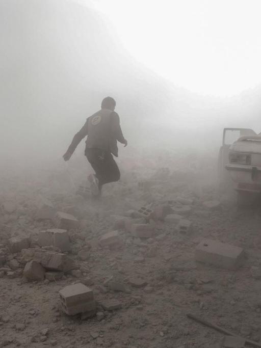 Ein syrischer Weißhelm rennt durch Rauch in der Stadt Douma nahe Damaskus, die von Regimegegnern gehalten wird.