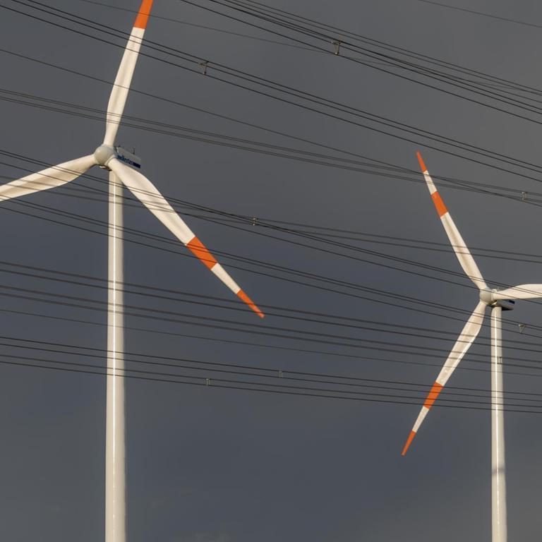 Dunkle Regenwolken sind hinter zwei Windkraftanlagen aufgezogen. Dunkle Regenwolken sind hinter zwei Windkraftanlagen aufgezogen.