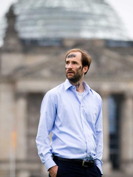 Mit beschmiertem Gesicht posiert Philipp Ruch vom "Zentrum für Politische Schönheit" am 08.08.2012 vor dem Reichstag in Berlin für den Fotografen.