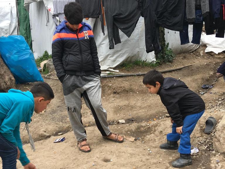Kinder spielen, in einen sorglosen Moment, mit Murmeln in einem Flüchtlingslager auf Lesbos.