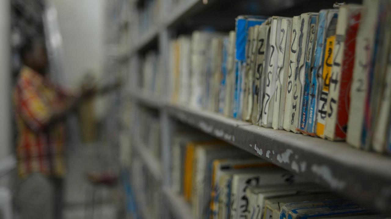 Die Archivbestände - überwiegend Tonbänder und Cassetten - füllen viele Regalmeter im Archiv von Radio Mogadischu. Das Foto zeigt die Regale, im Hintergrund: ein Mitarbeiter beim Sortieren.