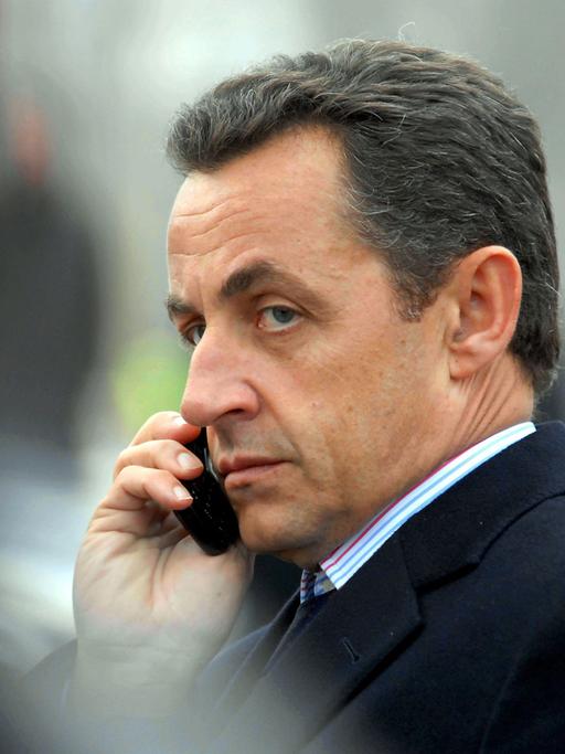 Nicolas Sarkozy telefoniert mit einem Handy.