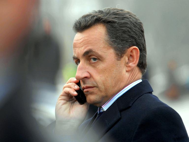 Nicolas Sarkozy telefoniert mit einem Handy.