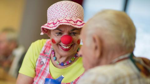 Eine als Clown verkleidete Mitarbeiterin eines Seniorenheims beschäftigt sich in Heilbronn mit einem Bewohner.