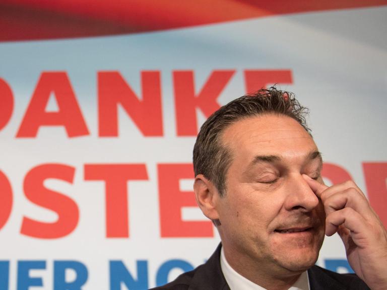Heinz Christian Strache von der FPÖ reibt sich die Augen vor einem Plakat "Danke, Österreich"