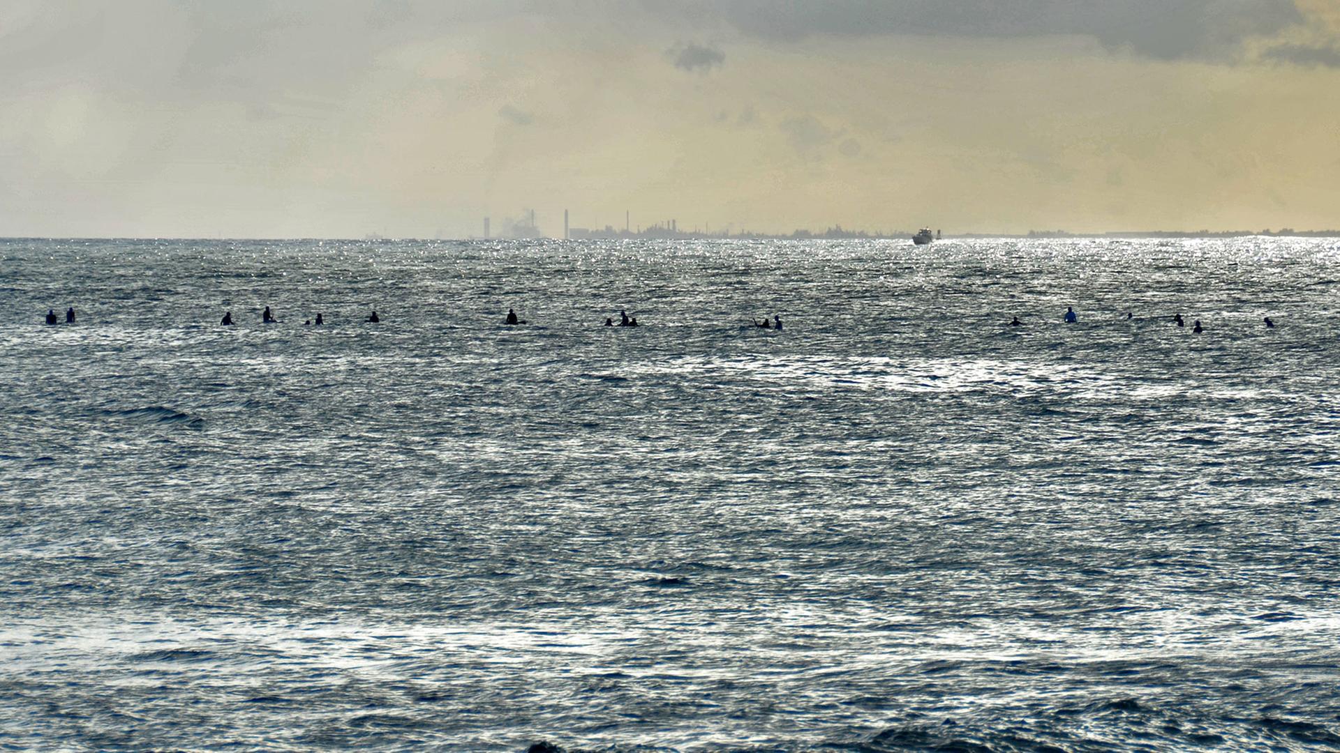 Surfer in der Abendsonne auf dem Pazifischen Ozean vor der Küste Hawaiis