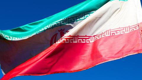 Iranische Flagge weht vor blauem Himmel
