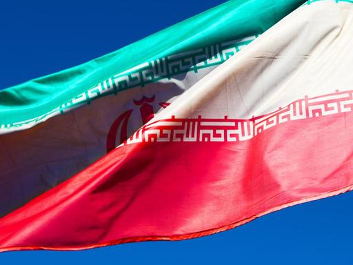 Iranische Flagge weht vor blauem Himmel