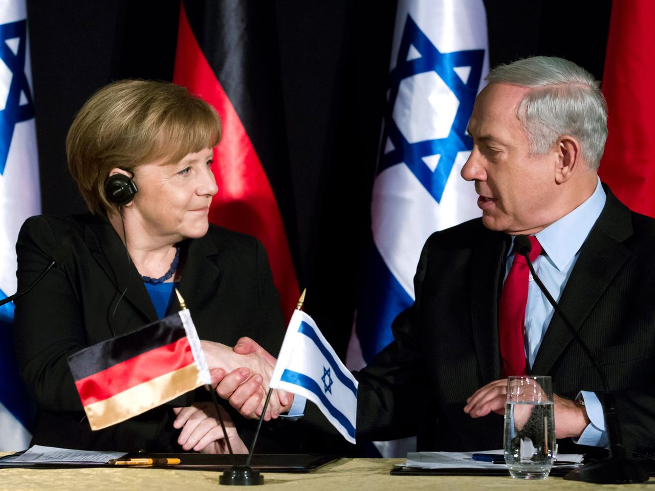 Bundeskanzlerin Angela Merkel und Benjamin Netanjahu schütteln die Hand.