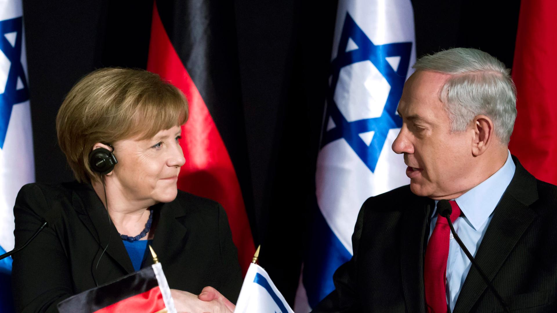 Bundeskanzlerin Angela Merkel und Benjamin Netanjahu schütteln die Hand.