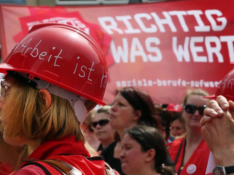 Erzieher und Erzieherinnen mit roten Plastikhelmen beteiligen sich an einer Demonstration.