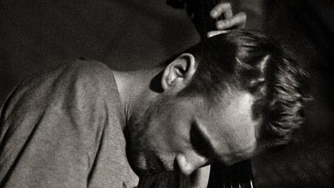 Der Bassist ist auf einem s/w Bild vertieft in sein Spiel zu sehen