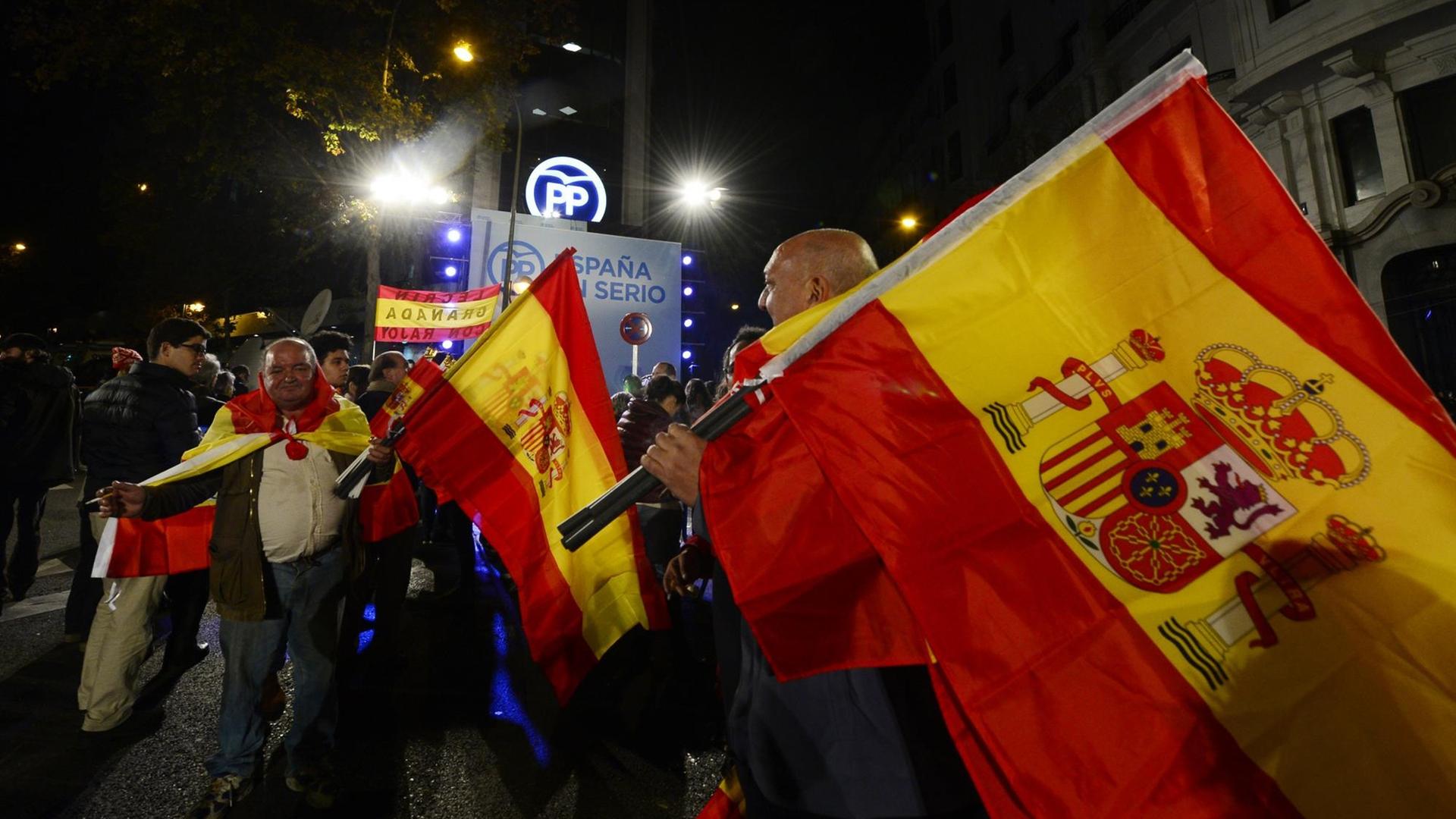 Unterstützer der Volkspartei (PP) schwenken spanische Flaggen vor der Parteizentrale in Madrid, nachdem erste Ergebnisse der Parlamentswahl bekannt wurden.