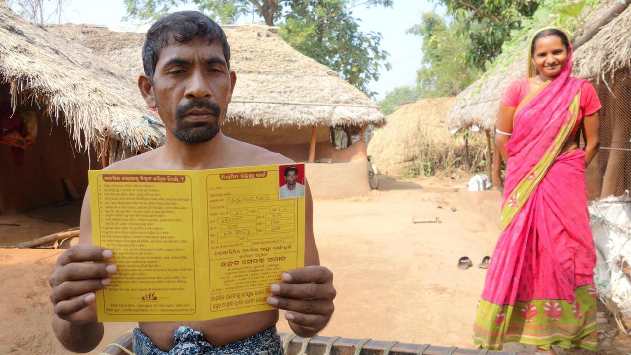 Anand Mahanta aus Horidapal achtet sorgsam auf die Behandlung seiner Schizophrenie. Er hält einen Medikamenten-Zettel hoch. Das freut seine Frau, die hinter ihm lächelnd steht.