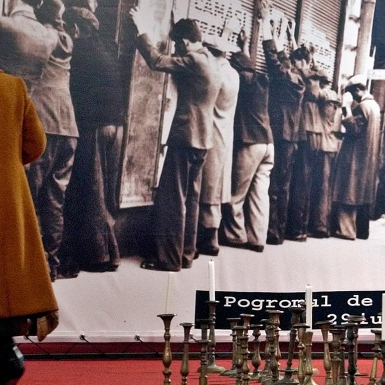 Eine ältere Frau steht vor einer Schwarz-Weiß-Aufnahme in einer Holocaust-Ausstellung in Bukarest. Das Foto zeigt von rumänischen Sicherheitskräften umstellte Juden in Iasi im Jahr 1941.
