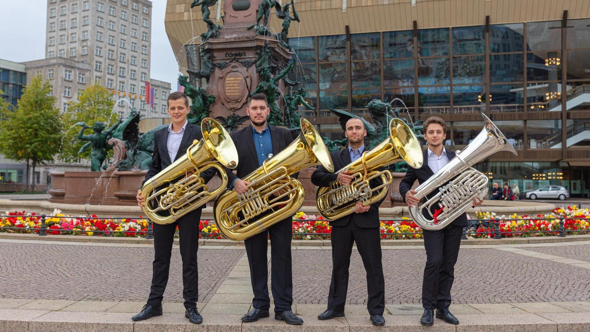 Vier Musiker stehen mit ihren Instrumenten vor dem Gewandhaus Leipzig